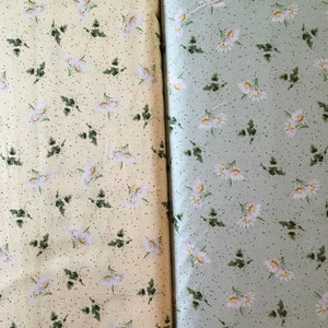May include: Two fabric swatches with a white daisy floral pattern on a light yellow background and a light green background.
