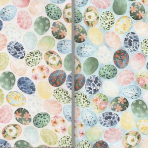 May include: Two fabric patterns featuring watercolor Easter eggs. The eggs are in various colors, including pink, blue, green, and yellow, and are decorated with floral and patterned designs. The background is a light cream and light blue.