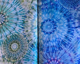 May include: A close-up of two fabric swatches with a tie-dye pattern. The fabric on the left is a light blue and green color with a white background. The fabric on the right is a light blue and purple color with a white background.