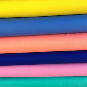 May include: Stack of six fabric rolls in different colors: yellow, blue, coral, navy blue, pink, and teal.