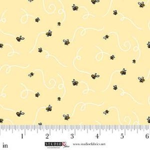 May include: Yellow fabric with a repeating pattern of cartoon bees and white swirly lines. The bees are black and yellow. The fabric is measured in inches.