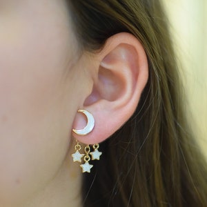 Model showcasing a pair of unique front-back earrings featuring a pearl white crescent moon at the front and three dangling stars at the back. These hypoallergenic earrings add a fun, starry night theme to any outfit.