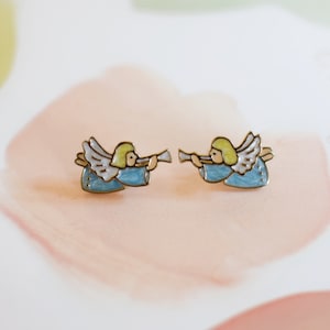 May include: A pair of gold-tone angel earrings with blue and white enamel. Each angel is playing a trumpet.