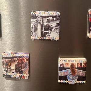 May include: Four square fridge magnets with photos and text. The first magnet has a photo of a concert crowd with the text "Long Live". The second magnet has a photo of two women with the text "I Was There". The third magnet has a photo of a concert crowd with the text "Find Indianapolis 2023 Tour". The fourth magnet has a photo of a woman with the text "Remember This Moment".
