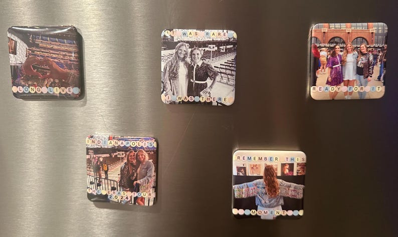May include: Four square fridge magnets with photos and text. The first magnet has a photo of a concert crowd with the text "Long Live". The second magnet has a photo of two women with the text "I Was There". The third magnet has a photo of a concert crowd with the text "Find Indianapolis 2023 Tour". The fourth magnet has a photo of a woman with the text "Remember This Moment".