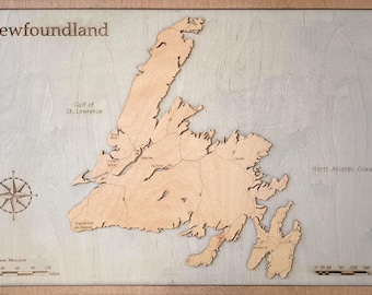 Op de afbeelding: Een houten kaart van Newfoundland, Canada, met de naam van de provincie bovenaan en de Golf van St. Lawrence en de Noord-Atlantische Oceaan met labels. De kaart is verdeeld in regio's met labels voor de namen van steden. Een kompasroos en schaalbalken zijn inbegrepen.