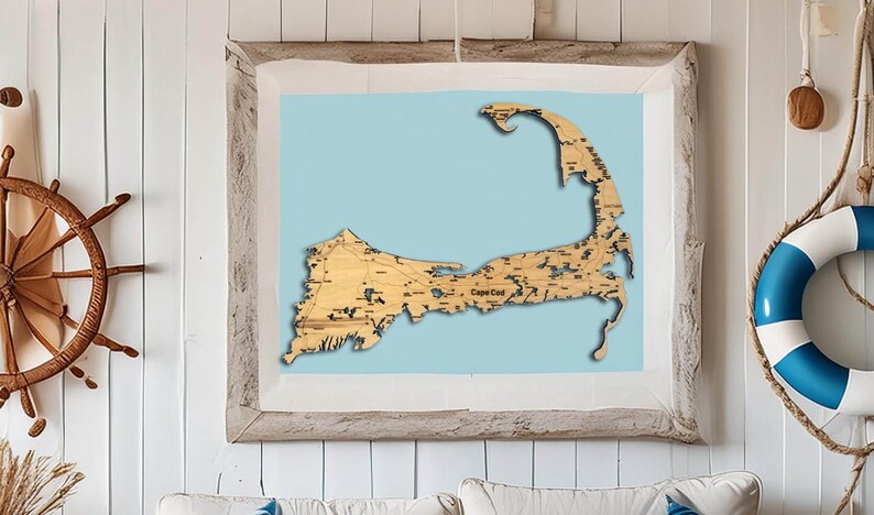 May include: A wooden map of Cape Cod, with detailed roads and waterways, is framed in a light wood frame and displayed on a white wall.