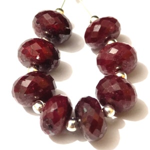 Op de afbeelding: Een streng van acht facetgeslepen robijn kralen, elke kraal is ongeveer 10 mm in diameter, geregen op een zilveren draad.
