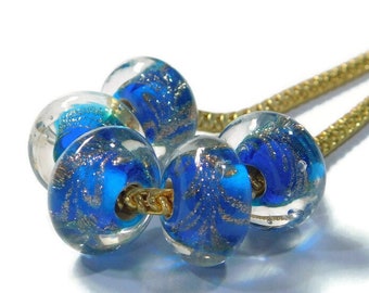 May include: A gold chain necklace with five blue glass beads. The beads have a sparkly, iridescent finish and a swirling pattern.