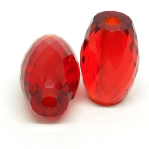May include: Two red faceted glass beads, one larger than the other, with a hole through the center.