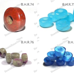 May include: An assortment of gemstone beads in various shapes and colors. Includes a large, red-brown bead with a central hole, several light blue donut-shaped beads, a collection of light green and purple beads, and a group of blue, cone-shaped beads. The beads are displayed on a white surface.