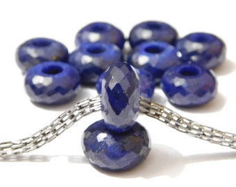 May include: A strand of silver chain with a stack of faceted sapphire beads. The beads are a deep blue color and have a round shape.