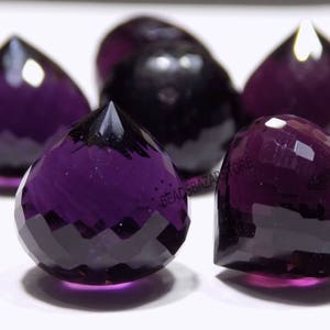 Könnte beinhalten: Fünf facettierte violette Amethyst-Edelsteinkugeln. Die Kugeln sind tropfenförmig und haben eine glänzende, polierte Oberfläche.