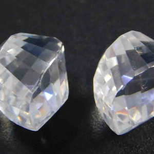 May include: Two clear, faceted, crystal-like stones with a diamond shape.