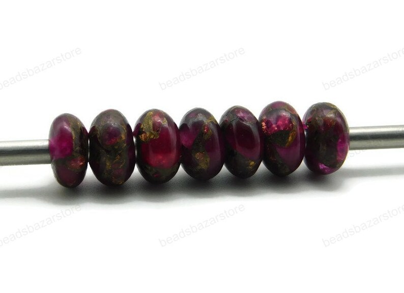 May include: A strand of eight round, dark purple beads with gold flecks. The beads are strung on a silver wire.