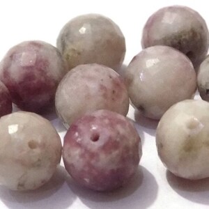 May include: A collection of ten faceted gemstone beads in shades of pink, white, and gray. The beads are round and have a smooth, polished finish.