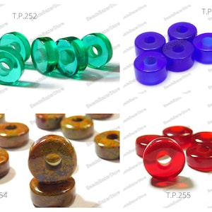 May include: Assortment of round glass beads with holes in the center. The beads are green, blue, red, and brown with a mottled pattern. The beads are labeled with the product code T.P. 252, T.P. 253, T.P. 254, and T.P. 255.