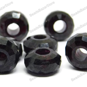 Puede incluir: Seis cuentas de cristal facetadas de color morado oscuro con un agujero en el centro. Las cuentas son redondas y tienen un acabado brillante.