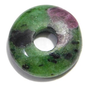 Può includere: Un tallone di pietra preziosa a forma di ciambella verde, rosa e nero con un foro al centro.