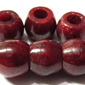 May include: Six deep red ruby gemstone beads with a hole through the centre. The beads are smooth and polished.
