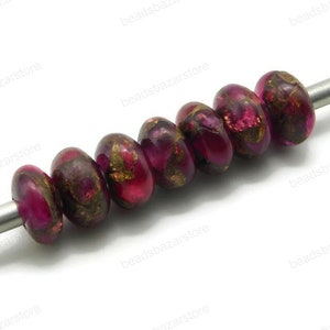 May include: A strand of eight round, pink and gold glass beads with a metallic finish. The beads are strung on a silver wire.
