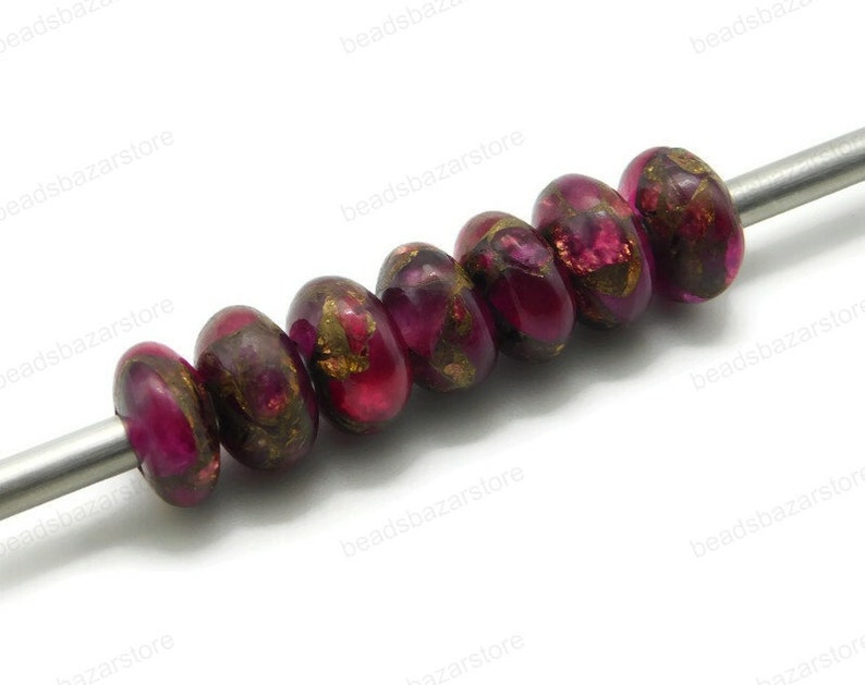 May include: A strand of eight round, pink and gold glass beads with a metallic finish. The beads are strung on a silver wire.