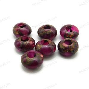 May include: Eight round, pink and gold beads with a hole in the centre. The beads have a speckled, marbled appearance.