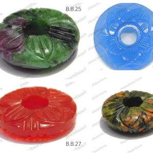 May include: Four carved gemstone beads with floral designs. The beads are green, blue, red, and green and brown. The beads are labeled B.B.25, B.B.26, B.B.27, and B.B.28.