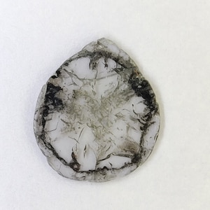 May include: A clear, round, glass pendant with a dark grey, starburst pattern.