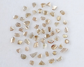 May include: A collection of brown rough diamonds, also known as raw diamonds, in various shapes and sizes. These diamonds are unpolished and have a natural, earthy appearance.