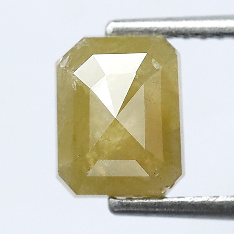 May include: A yellow emerald cut diamond with a rectangular shape.