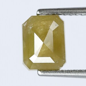 May include: A yellow, emerald cut diamond with a rectangular shape.