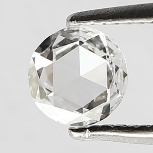 K&ouml;nnte beinhalten: Ein klarer, runder, facettierter Diamant-Edelstein, der von einer Pinzette gehalten wird. Der Diamant ist ein Brillantschliff mit vielen Facetten.