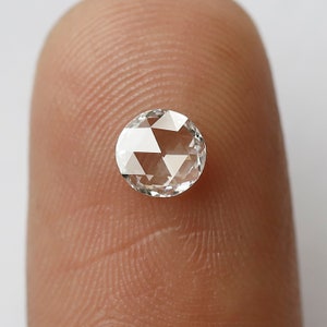 K&ouml;nnte beinhalten: Ein runder, klarer, facettierter Diamantenstein auf einem Finger.