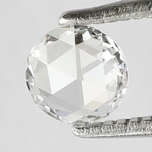 K&ouml;nnte beinhalten: Ein klarer, runder, facettierter Diamant-Edelstein, der in einer Pinzette gehalten wird.