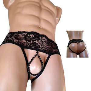 Puede incluir: Ropa interior de encaje negro con detalle de cuentas. La ropa interior presenta un diseño de encaje floral a lo largo de la cintura y un diseño de tanga. Una hebra de cuentas negras en forma de lágrima cuelga de la parte delantera.