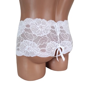 May include: White lace underwear with a floral pattern and a bow tie at the back.