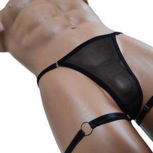 May include: Black mesh lingerie with a garter belt and a ring detail. The lingerie is made of a sheer fabric and has a delicate design.