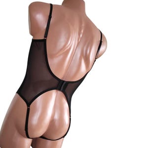 Könnte beinhalten: Schwarzer Netzbody mit tiefem Rücken und verstellbaren Trägern. Der Body hat einen Ausschnitt im Rücken und einen Haken- und Ösenverschluss.