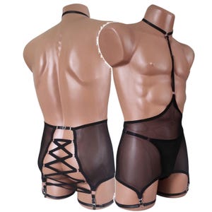 May include: A black mesh body harness and shorts set featuring a choker collar, thin adjustable straps, and silver-toned metal rings. The back of the shorts includes a decorative lace-up design with crisscross straps and integrated garter loops.