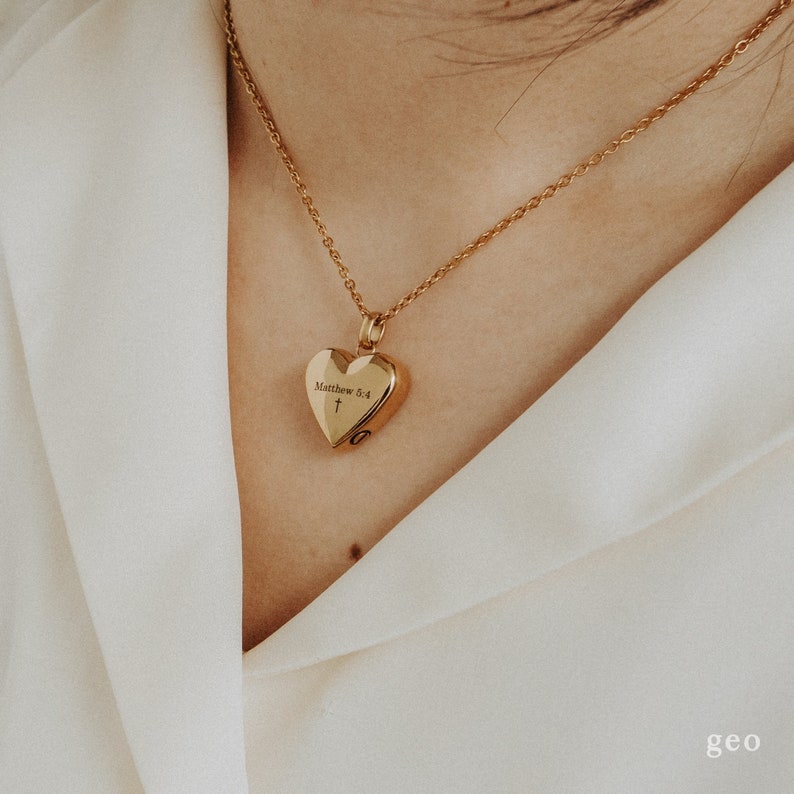 May include: A gold heart-shaped locket necklace with the inscription "Matthew 6:4" and a small cross.
