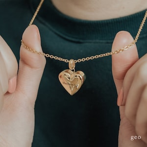 May include: A gold chain necklace with a heart-shaped pendant. The pendant has the words "Matthew 5:4" engraved on it, along with a small cross.