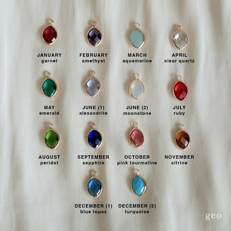 May include: A chart of birthstone charms for each month of the year. The charms are gold-toned with a variety of colored gemstones. January is garnet, February is amethyst, March is aquamarine, April is clear quartz, May is emerald, June (1) is alexandrite, June (2) is moonstone, July is ruby, August is peridot, September is sapphire, October is pink tourmaline, November is citrine, December (1) is blue topaz, and December (2) is turquoise.