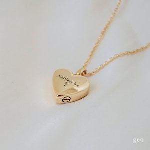 May include: Gold heart-shaped pendant necklace with a cross and the inscription "Matthew 5:4".