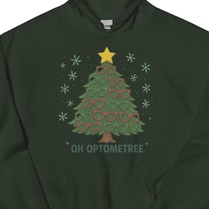 May include: Dark green hoodie with a Christmas tree design made of eyeglasses. The tree is topped with a yellow star and surrounded by snowflakes. The text "OH OPTOMETREE" is printed below the tree.