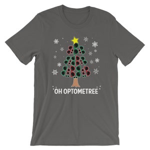 May include: A dark gray t-shirt with a Christmas tree made of sunglasses. The tree has a yellow star on top and is surrounded by snowflakes. The text "OH OPTOMTREE" is printed below the tree.