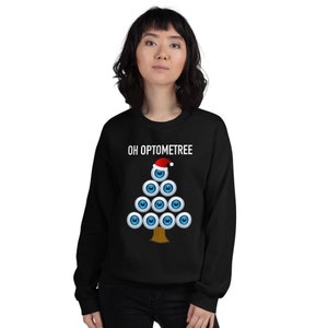 May include: Black sweatshirt with a white Christmas tree design made of eyeballs. The tree is topped with a Santa hat. The text "OH OPTOMTREE" is printed above the tree.
