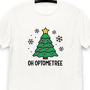 May include: White t-shirt featuring a green Christmas tree design with eye-shaped ornaments and a yellow star on top. The text "OH OPTOMETREE" is printed below the tree, surrounded by snowflake and dot graphics.