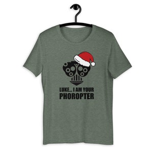 May include: A green t-shirt with a black and white image of a phoropter wearing a Santa hat. The text "LUKE... I AM YOUR PHOROPTER" is printed below the image.