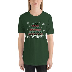 May include: Green short-sleeved t-shirt with a white Christmas tree design made of sunglasses. The text "OH OPTOMETREE" is written below the tree.